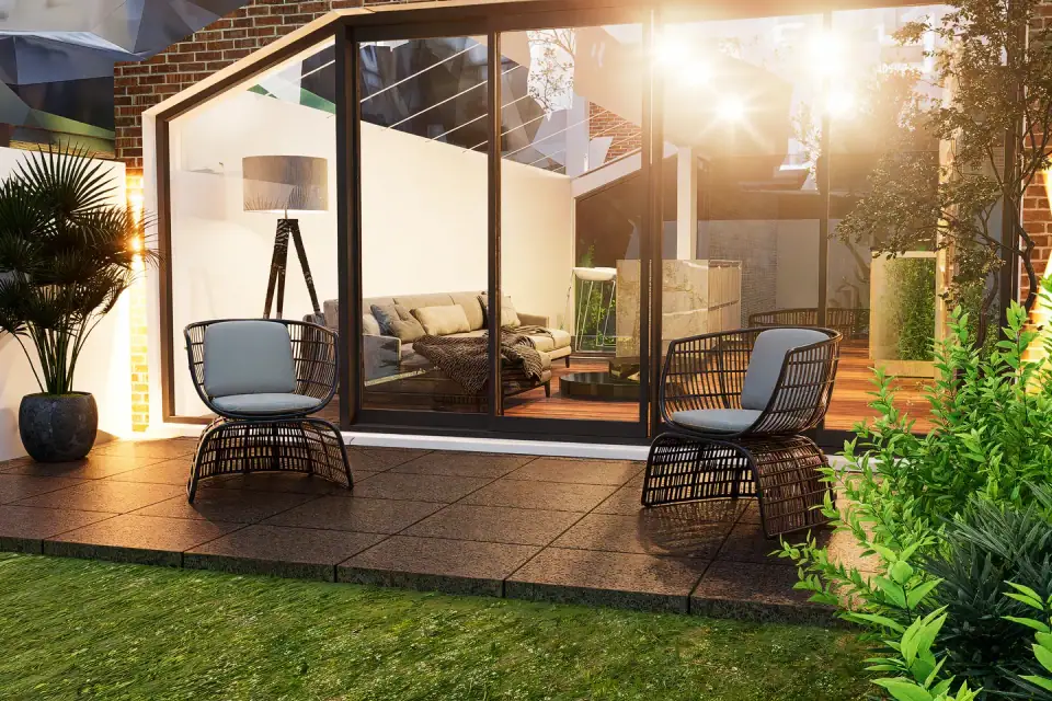 Glazed garden room with a sofa and floor lamp, opening onto a timber terrace