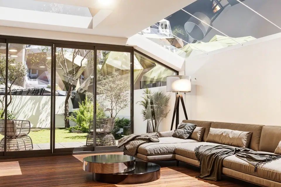 Living room beneath a glazed roof, with a leather sofa, timber floor and sliding doors to the garden