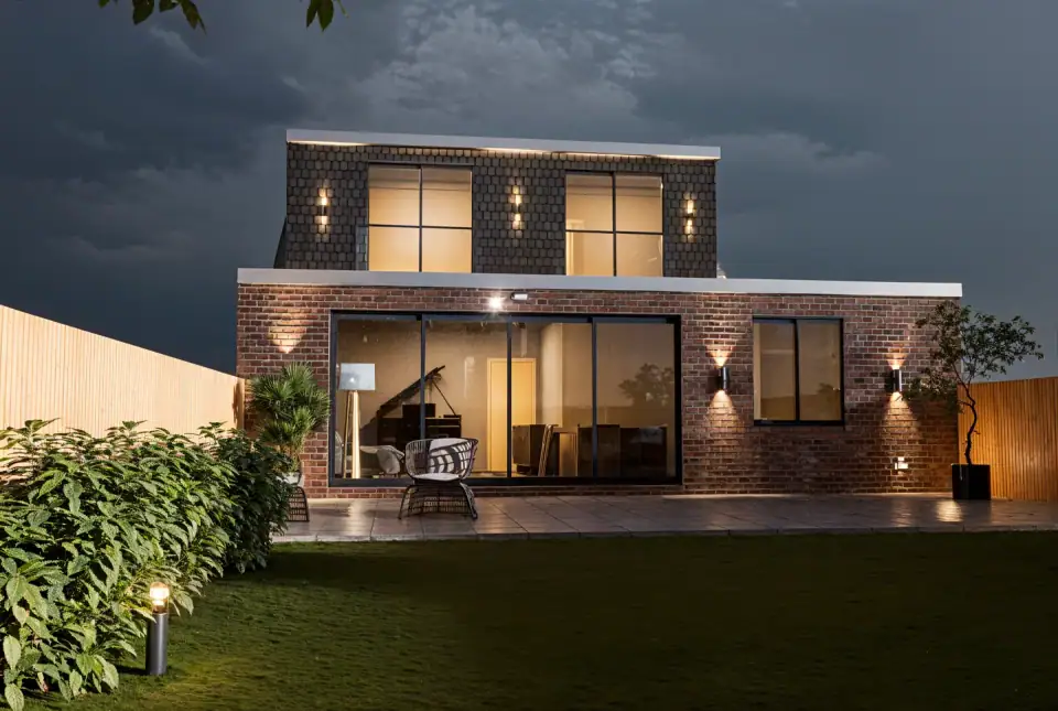 Rear of a remodelled bungalow at dusk, a grand piano visible in the lit music room
